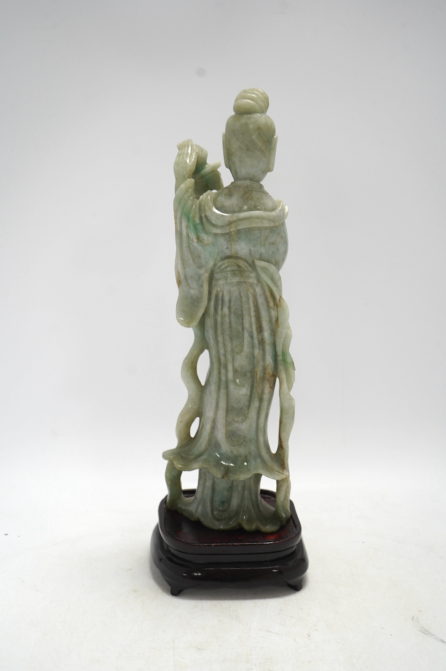 A Chinese jadeite carving of Guanyin, on associated hardwood stand, 38cm high. Condition - fair